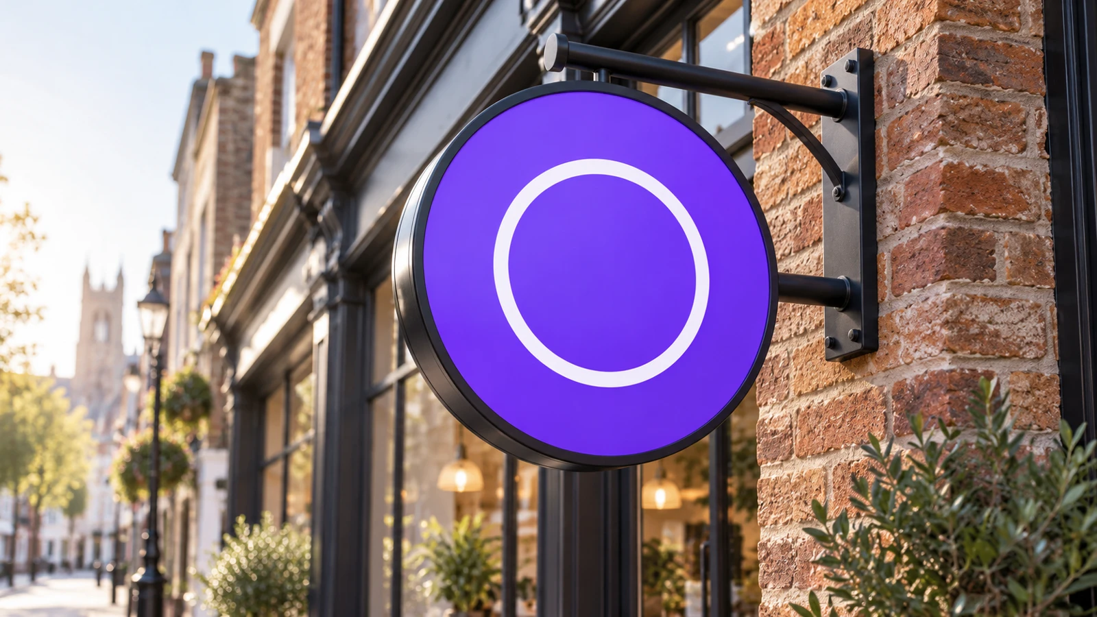 Round illuminated projecting sign on a wall bracket outside a high-street shop